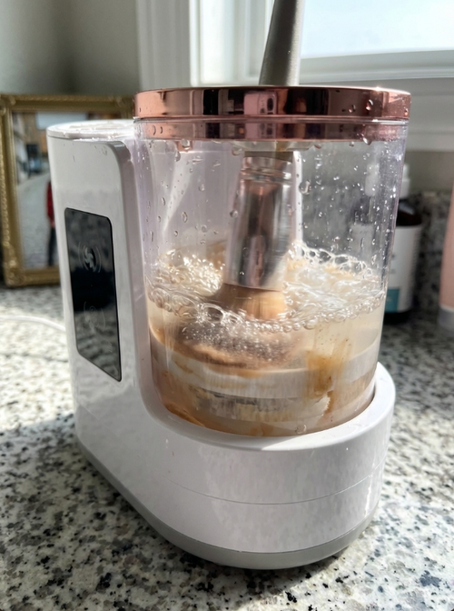 Aurevia Bliss makeup brush cleaning machine and dryer with multiple brush attachments on a clean white surface.